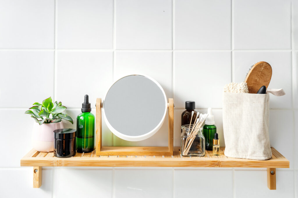 Close up of bamboo shelf in a bathroom with stainable organic cosmetics and reusable bottles and conatiners. Wellness and sustainability concept